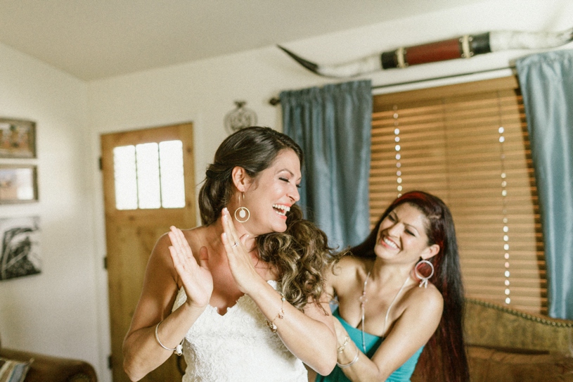 Bride getting her dress put on by her best friend at her farm house wedding by heather elizabeth photography