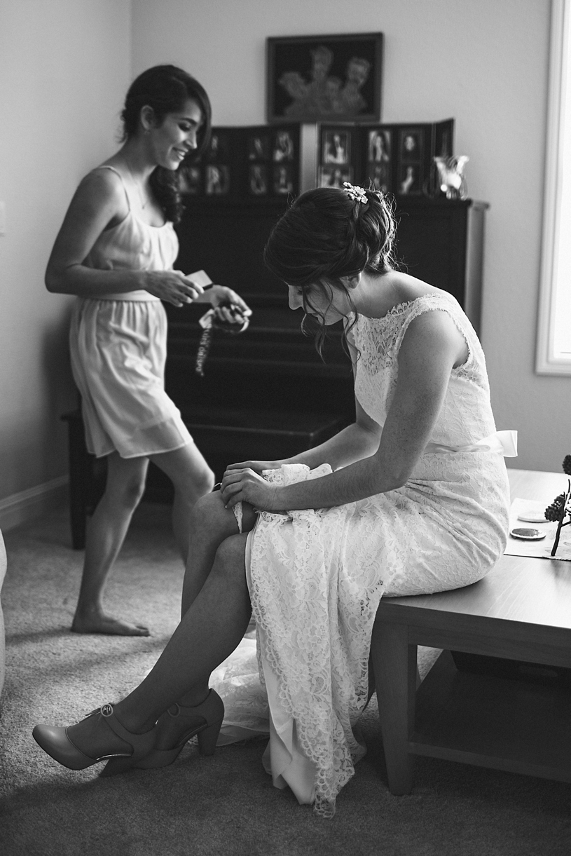 photo journalism of bride putting on her garter at a wedding in UC davis by heather elizabeth photography